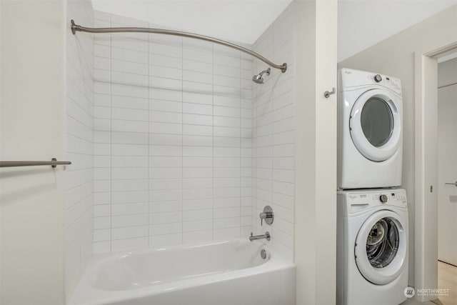 bathroom featuring stacked washer and dryer and tiled shower / bath