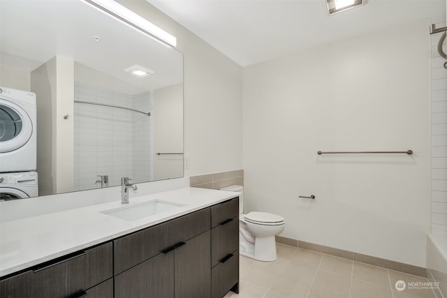 bathroom featuring stacked washer / drying machine, toilet, a tile shower, and vanity