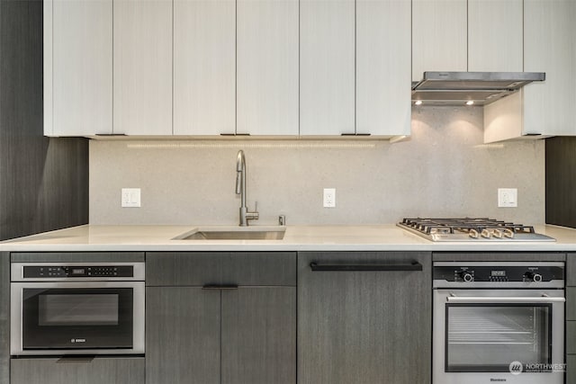 kitchen featuring gray cabinetry, decorative backsplash, sink, and appliances with stainless steel finishes