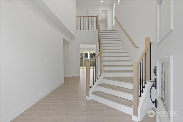 stairs featuring a high ceiling and hardwood / wood-style flooring