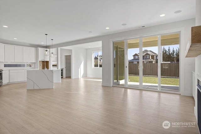 unfurnished living room with sink and light hardwood / wood-style flooring