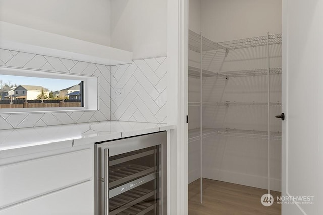 bar featuring wood-type flooring, wine cooler, and tasteful backsplash