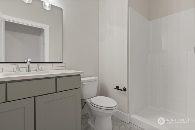 bathroom with tile patterned floors, vanity, toilet, and a shower