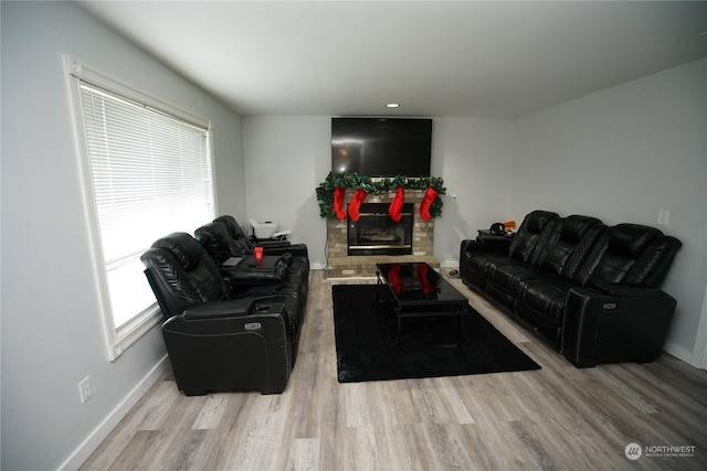 living room with a stone fireplace and light wood-type flooring