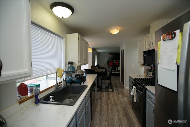 kitchen featuring dark hardwood / wood-style flooring, sink, white cabinetry, and black appliances