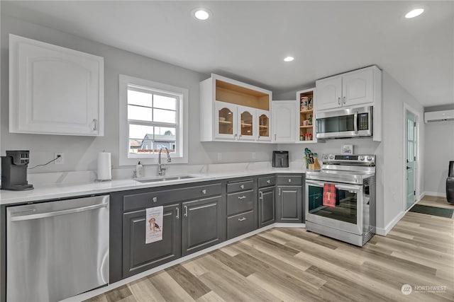 kitchen with stainless steel appliances, a wall mounted AC, sink, white cabinets, and gray cabinets