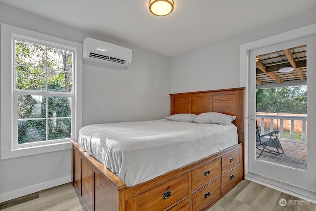 bedroom featuring a wall mounted air conditioner, light hardwood / wood-style floors, and multiple windows