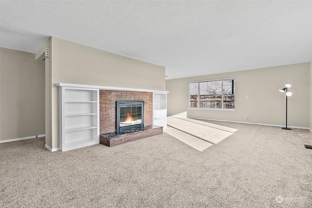 unfurnished living room featuring carpet flooring, built in shelves, a textured ceiling, and a brick fireplace