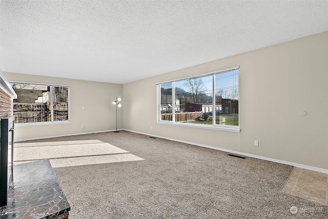 unfurnished living room with carpet flooring, a textured ceiling, and a brick fireplace