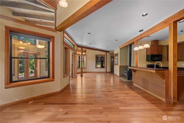 kitchen featuring vaulted ceiling with beams, kitchen peninsula, hanging light fixtures, and light hardwood / wood-style floors