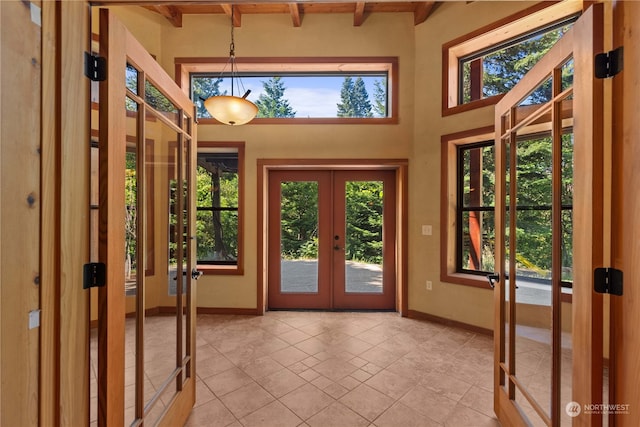 entrance foyer featuring beam ceiling, a wealth of natural light, and french doors