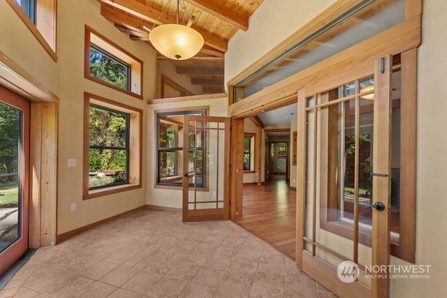 unfurnished sunroom featuring beam ceiling, french doors, and wooden ceiling