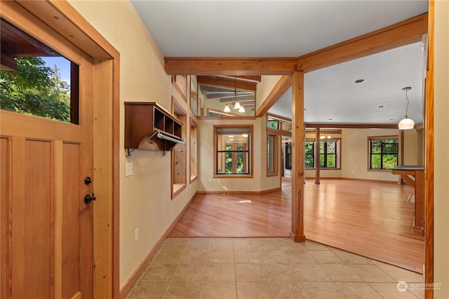 tiled foyer with a notable chandelier and beam ceiling