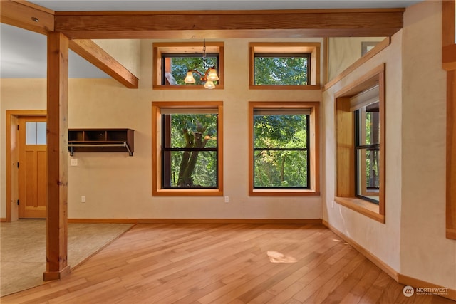 interior space with light wood-type flooring, an inviting chandelier, and a healthy amount of sunlight