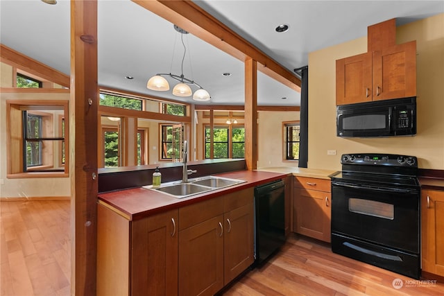 kitchen featuring kitchen peninsula, sink, black appliances, light hardwood / wood-style floors, and hanging light fixtures