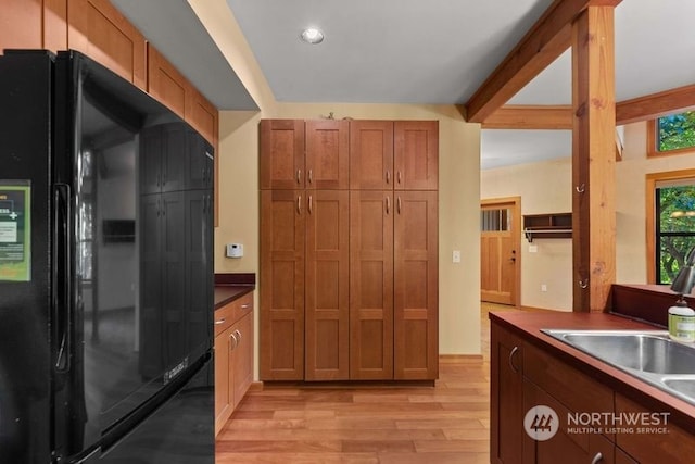 kitchen with black refrigerator, light hardwood / wood-style floors, and sink