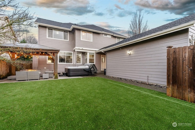 back house at dusk featuring an outdoor living space, a gazebo, a hot tub, and a yard