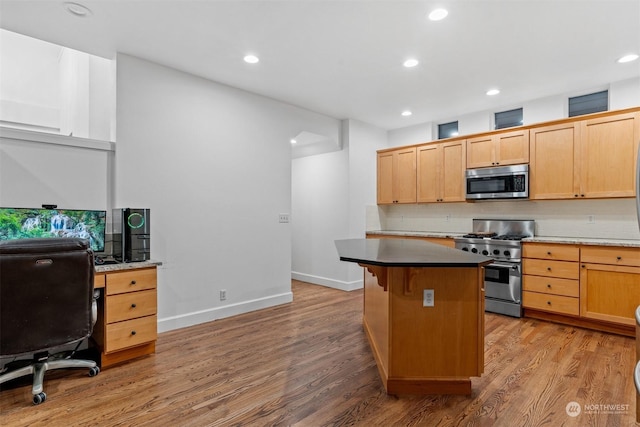 kitchen featuring a center island, light hardwood / wood-style flooring, a kitchen breakfast bar, stainless steel appliances, and backsplash