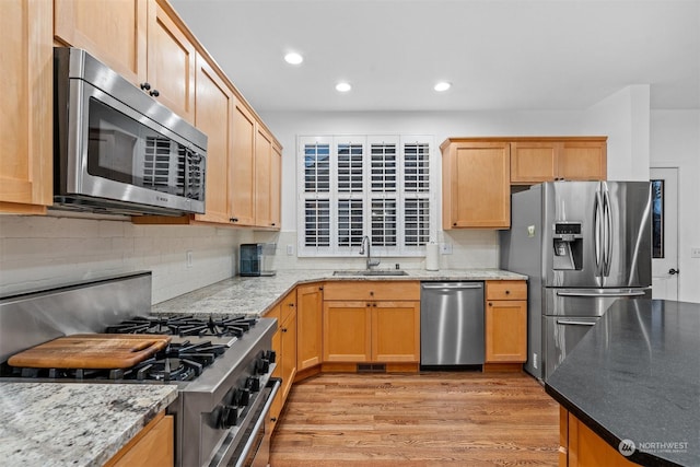 kitchen with tasteful backsplash, stainless steel appliances, light stone countertops, and sink