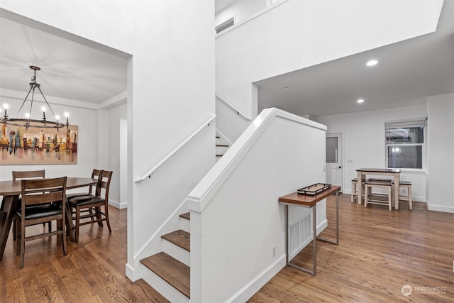 staircase with hardwood / wood-style floors and a notable chandelier