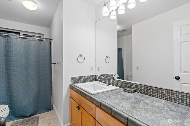 bathroom with tasteful backsplash, vanity, curtained shower, and toilet