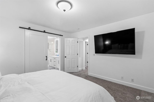 bedroom with dark colored carpet, ensuite bathroom, and a barn door