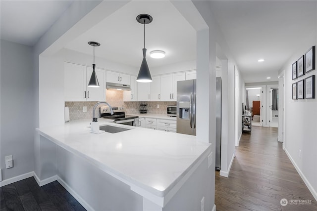 kitchen with appliances with stainless steel finishes, hanging light fixtures, kitchen peninsula, sink, and white cabinetry