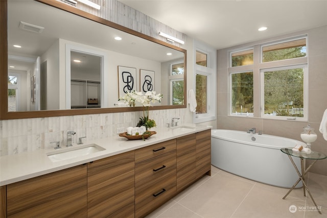 bathroom featuring vanity, backsplash, tile patterned flooring, a tub to relax in, and tile walls