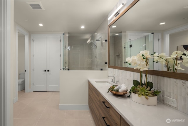 bathroom with tile patterned floors, vanity, a shower with shower door, and toilet