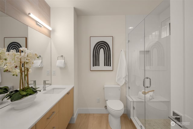 bathroom featuring wood-type flooring, vanity, toilet, and walk in shower