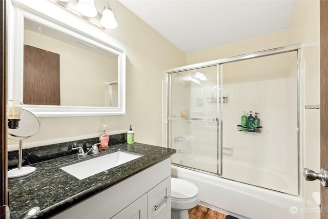 full bathroom featuring toilet, vanity, bath / shower combo with glass door, and hardwood / wood-style flooring