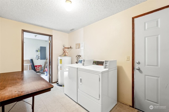 washroom featuring washing machine and dryer, electric water heater, and a textured ceiling