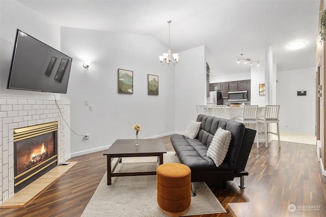 living room with a fireplace, vaulted ceiling, a notable chandelier, and dark hardwood / wood-style floors