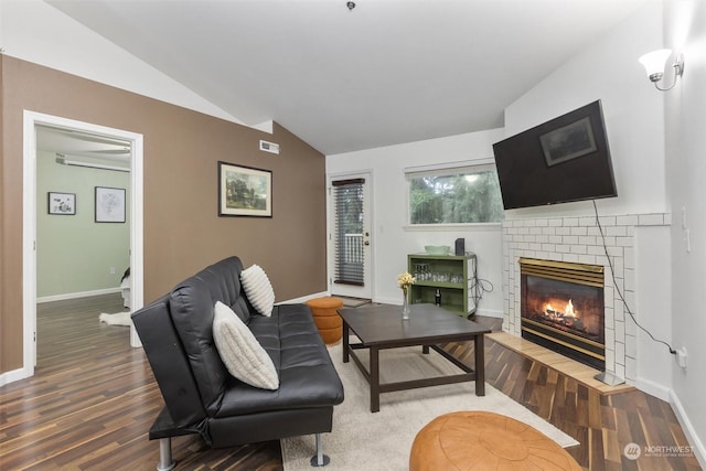 living room featuring a brick fireplace, vaulted ceiling, and hardwood / wood-style flooring