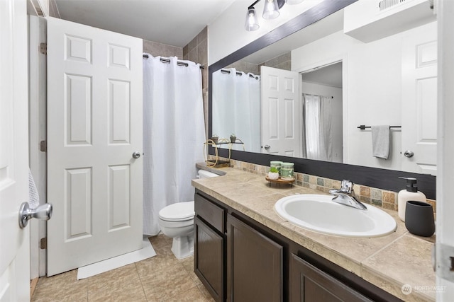 bathroom with toilet, vanity, tile patterned flooring, and backsplash