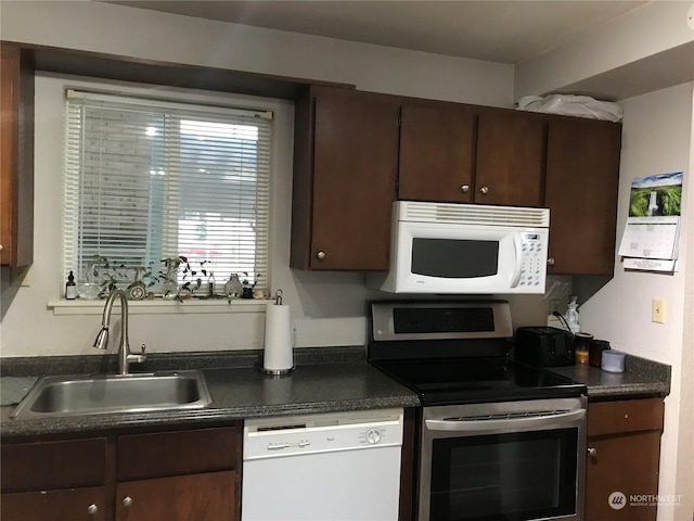 kitchen featuring white appliances, dark brown cabinetry, and sink