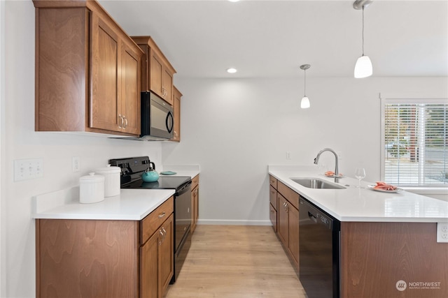 kitchen with black appliances, pendant lighting, kitchen peninsula, and sink