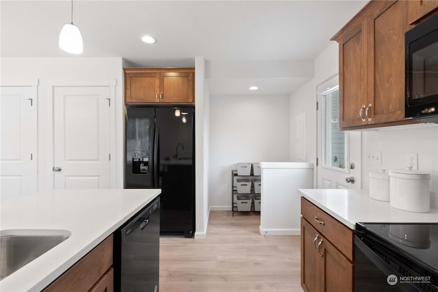 kitchen with sink, decorative light fixtures, light hardwood / wood-style floors, and black appliances