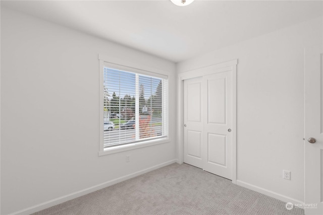 unfurnished bedroom featuring a closet and light colored carpet