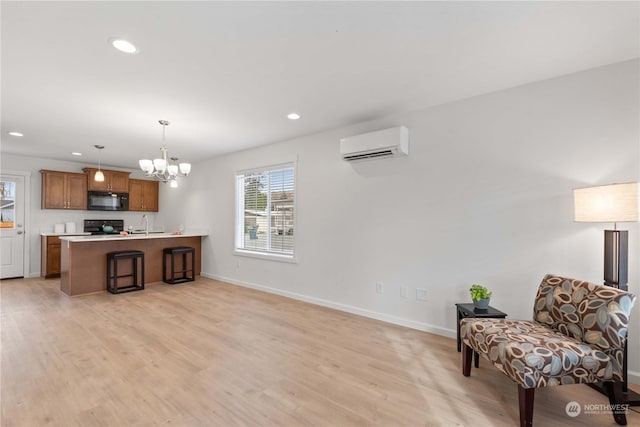 interior space featuring a wall mounted air conditioner, kitchen peninsula, black appliances, decorative light fixtures, and light hardwood / wood-style flooring