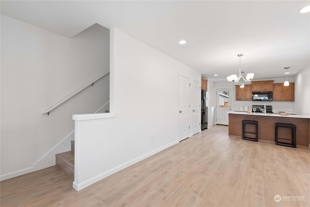 kitchen with an inviting chandelier, light hardwood / wood-style flooring, stainless steel fridge, decorative light fixtures, and range