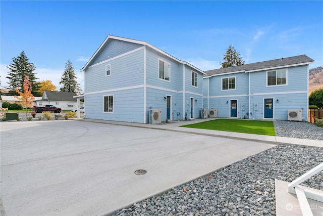 back of property featuring a lawn and ac unit