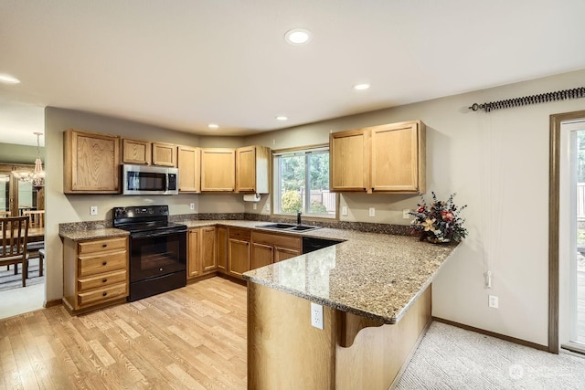 kitchen with light stone counters, kitchen peninsula, electric range, a breakfast bar area, and sink