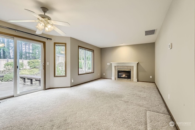 unfurnished living room featuring ceiling fan, light colored carpet, and a tiled fireplace