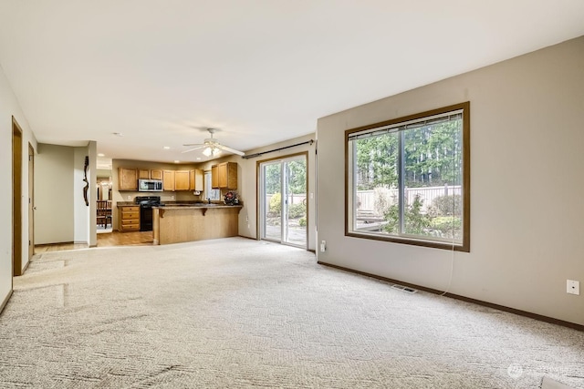 unfurnished living room featuring ceiling fan and light colored carpet