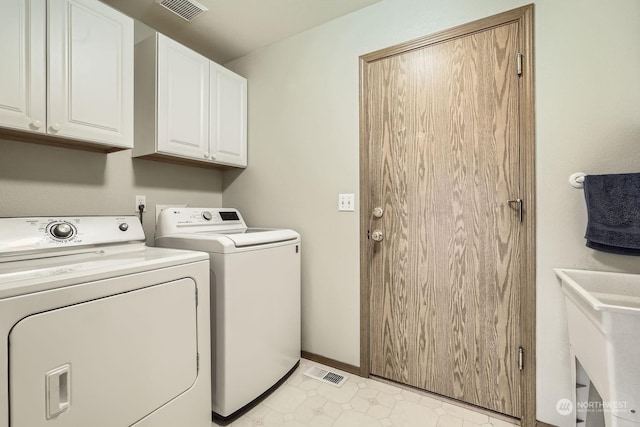 clothes washing area with separate washer and dryer and cabinets