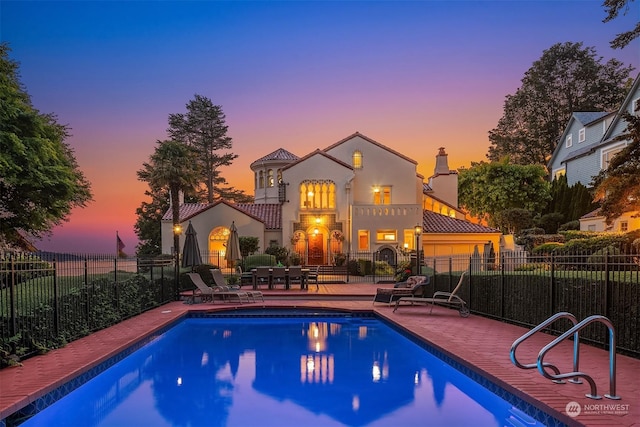 pool at dusk with a patio area