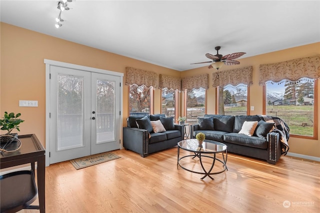 living room featuring ceiling fan, light hardwood / wood-style flooring, and french doors