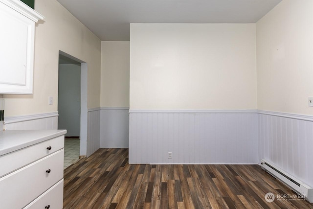 unfurnished room with a baseboard radiator and dark hardwood / wood-style floors