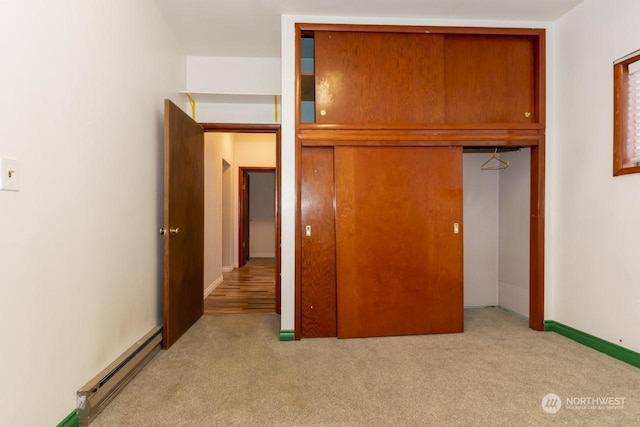 unfurnished bedroom featuring baseboard heating, light carpet, and a closet